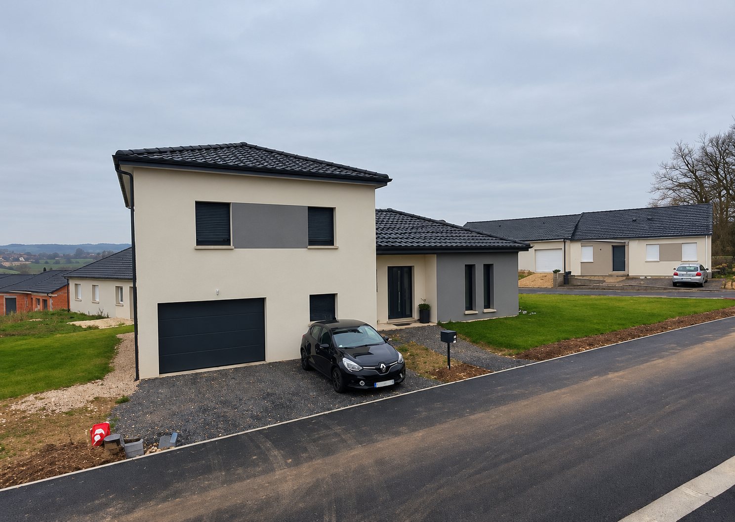 Une maison neuve à toit gris foncé et façade claire, avec garage et voiture noire dans l'allée, au sein d'un lotissement sous un ciel couvert.